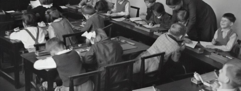 A vintage primary-school classroom scene in black & white