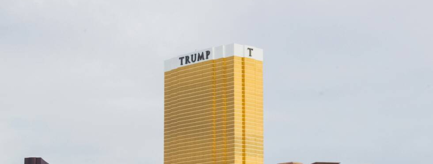 A photo of three towers in a skyline, with the Trump Tower in the middle, larger that the other two and gold.